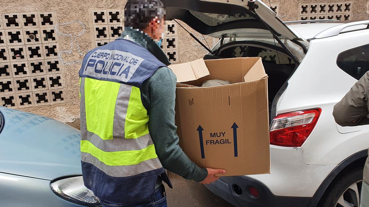 Un policía guarda una caja con efectos intervenidos en uno de los registros en Crevillent.