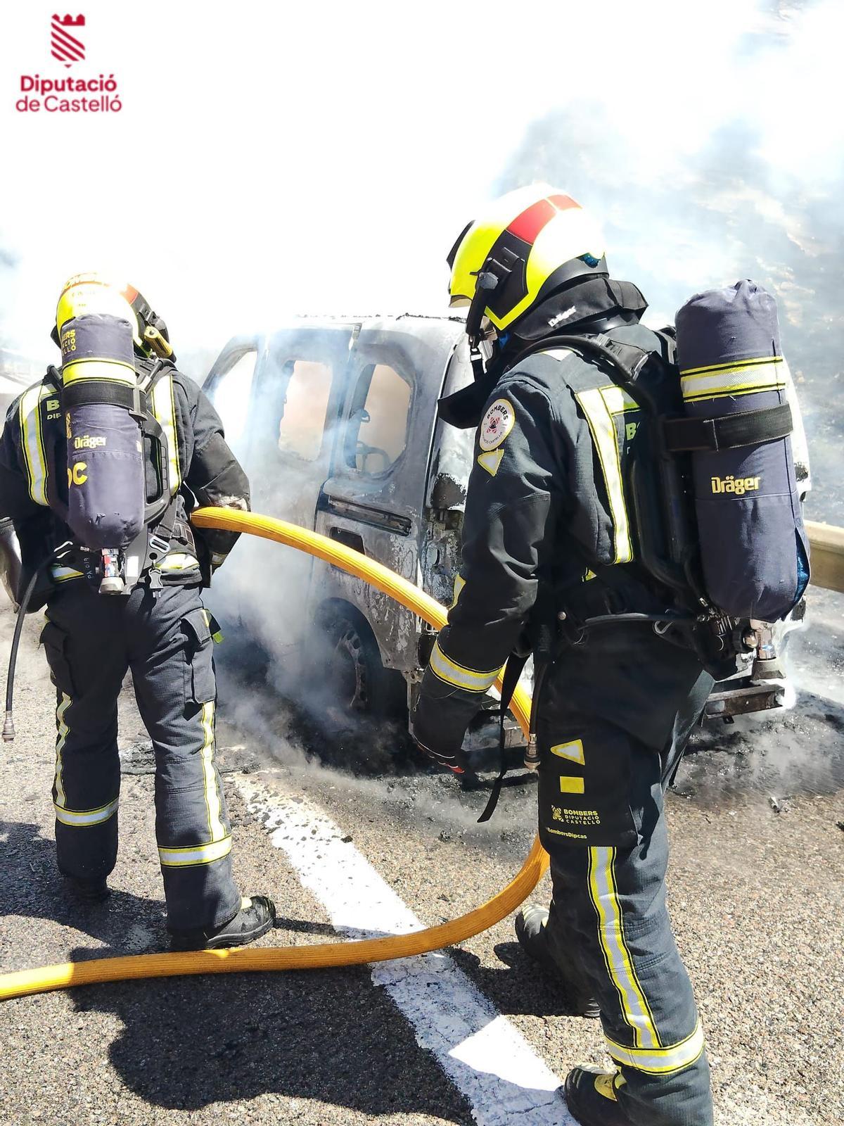 Los bomberos apagan el fuego en el coche este viernes en la AP-7.