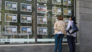 Dos mujeres miran las ofertas de venta de casas en una inmobiliaria.