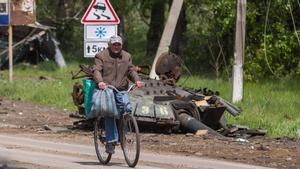 Un hombre monta en bici entre los restos de la batalla en Járkov.