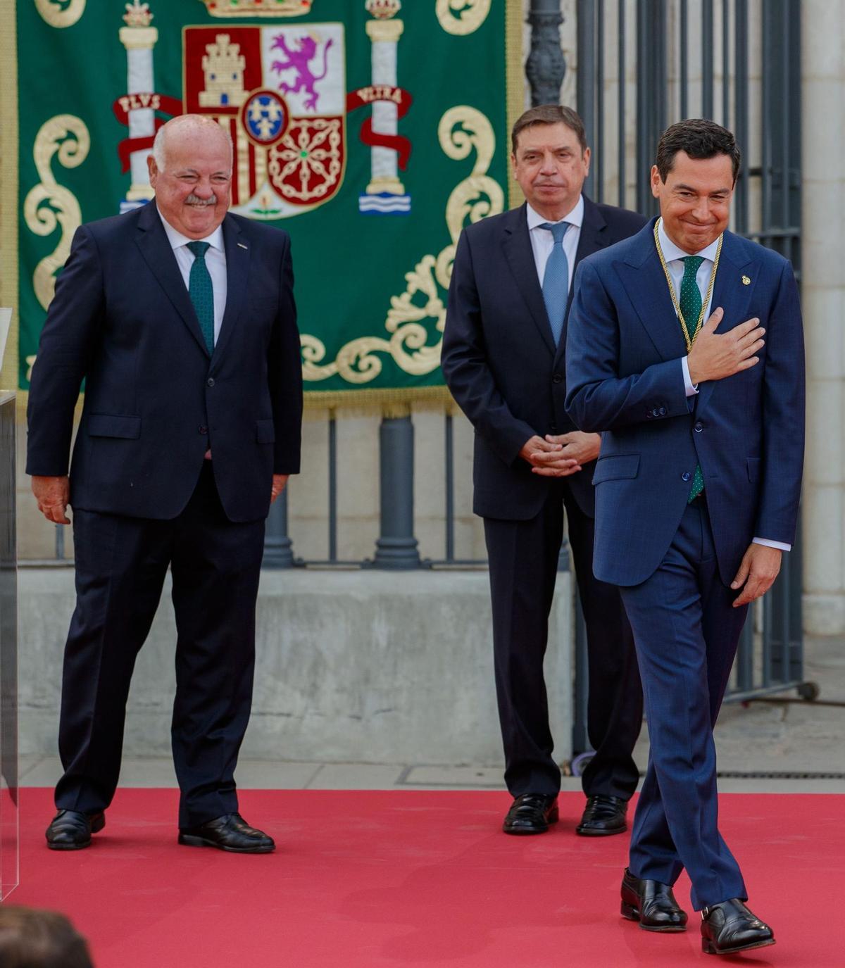 SEVILLA, 23/07/2022.- El presidente de la Junta de Andalucía, Juanma Moreno, junto al ministro de Agricultura, Luis Planas (c) y el presidente del Parlamento andaluz, Jesús Aguirre (i) tras jurar hoy sábado el cargo para un nuevo mandato tras la lectura del Real Decreto de nombramiento, en un acto que se ha desarrolla ante la fachada del Palacio de San Telmo de Sevilla, sede de la Presidencia. EFE/Julio Muñoz