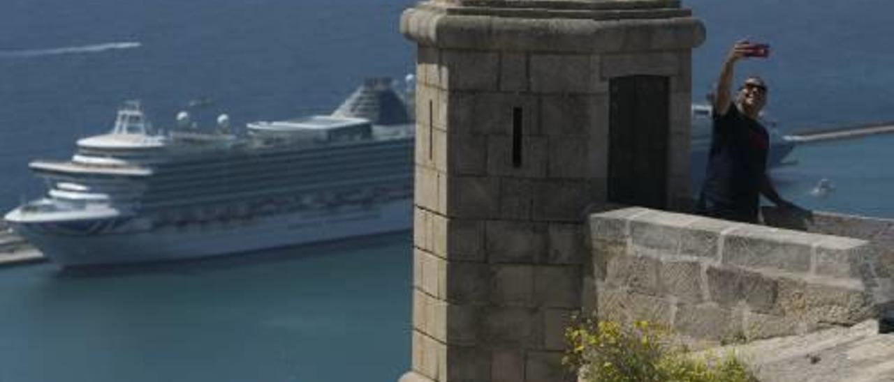 Un turista se hace un «selfy» en el castillo de Santa Bárbara el jueves. Al fondo uno de los cruceros.