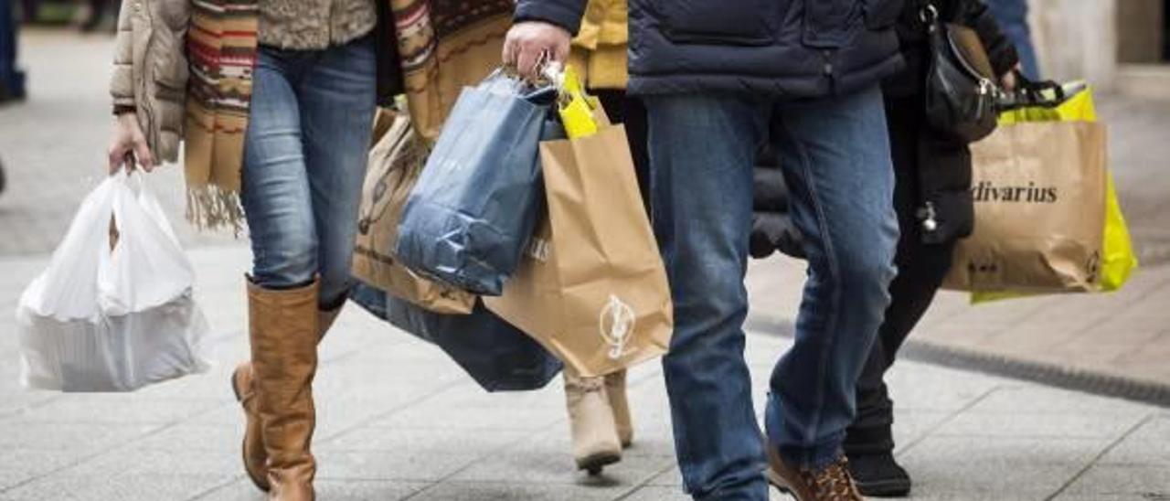 Varias personas, con bolsas, tras las compras que acaban de hacer.