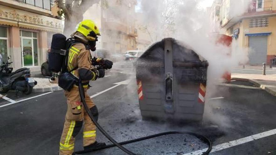 Un bombero extingue uno de los tres incendios de contenedores.