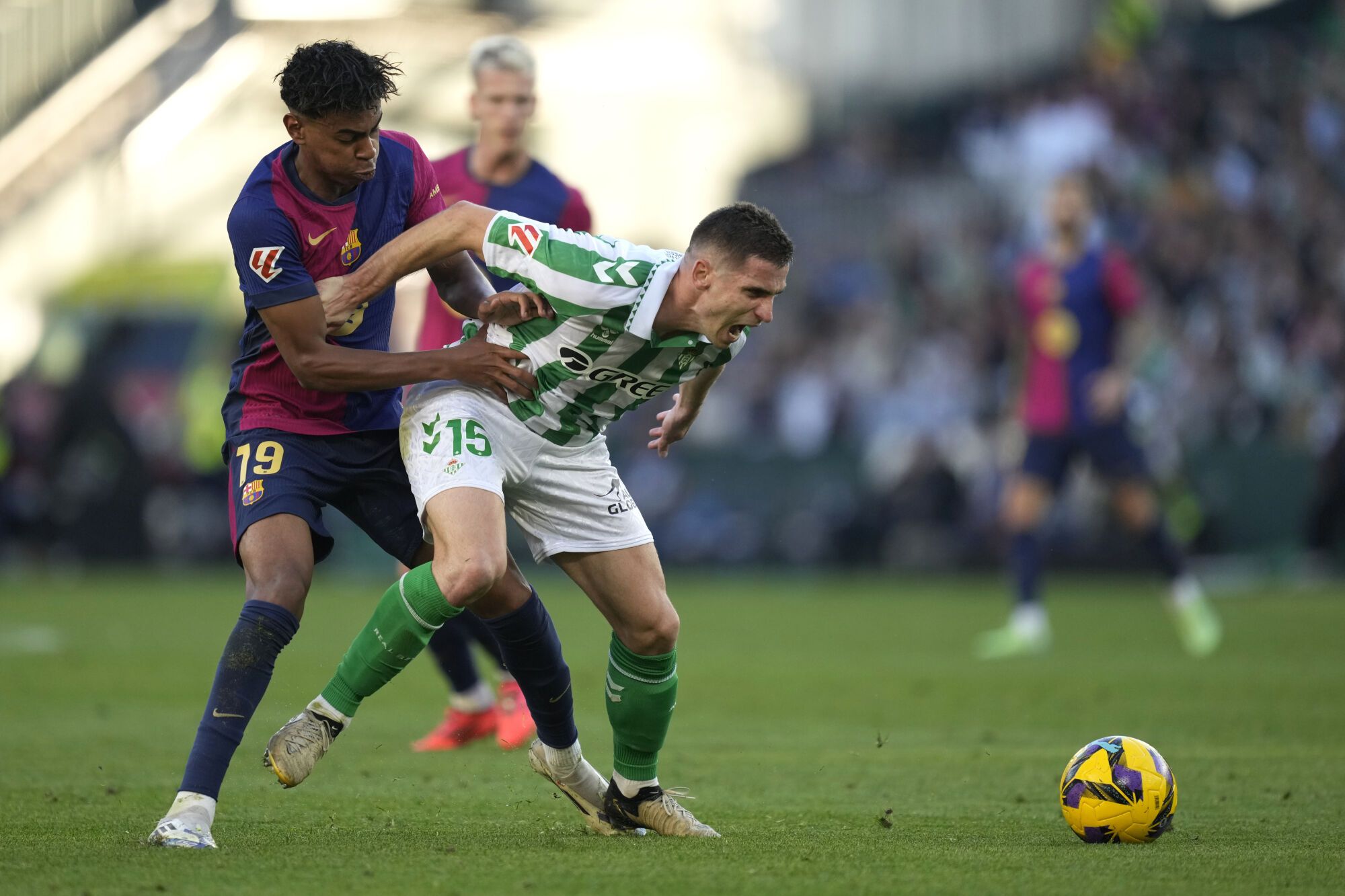 Barcelona's Lamine Yamal, left, challenges for the ball with Betis' Romain Perraud during a Spanish La Liga soccer match between Betis and Barcelona at the Benito Villamarin stadium in Seville, Spain, Saturday, Dec. 7, 2024. (AP Photo/Jose Breton)