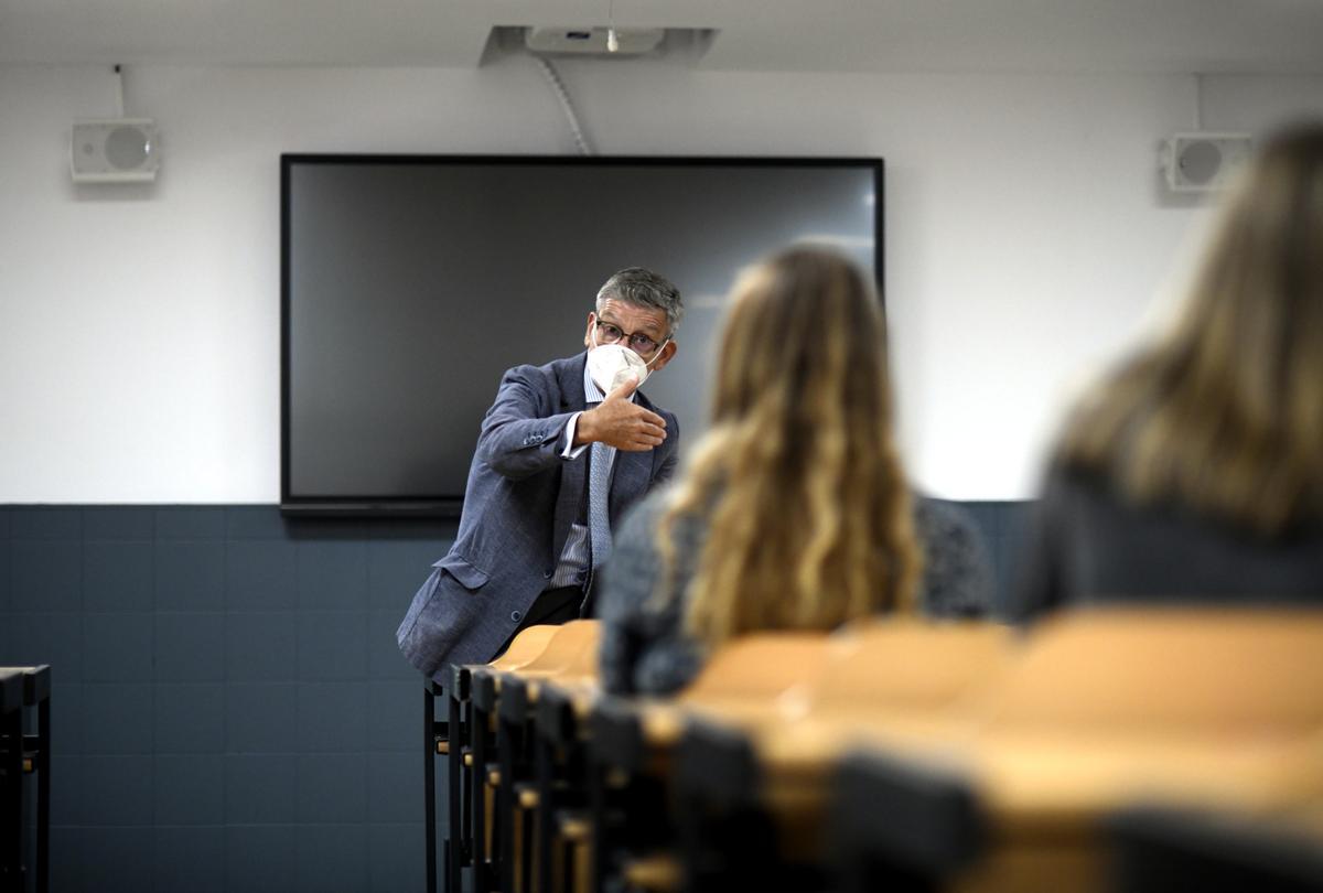 Un profesor da clase con mascarilla.
