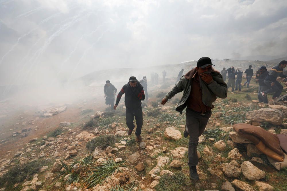 Manifestantes palestinos huyen del gas pimienta lanzado por las tropas israelís en las colonias israelís en la ciudad palestina de Ramala.