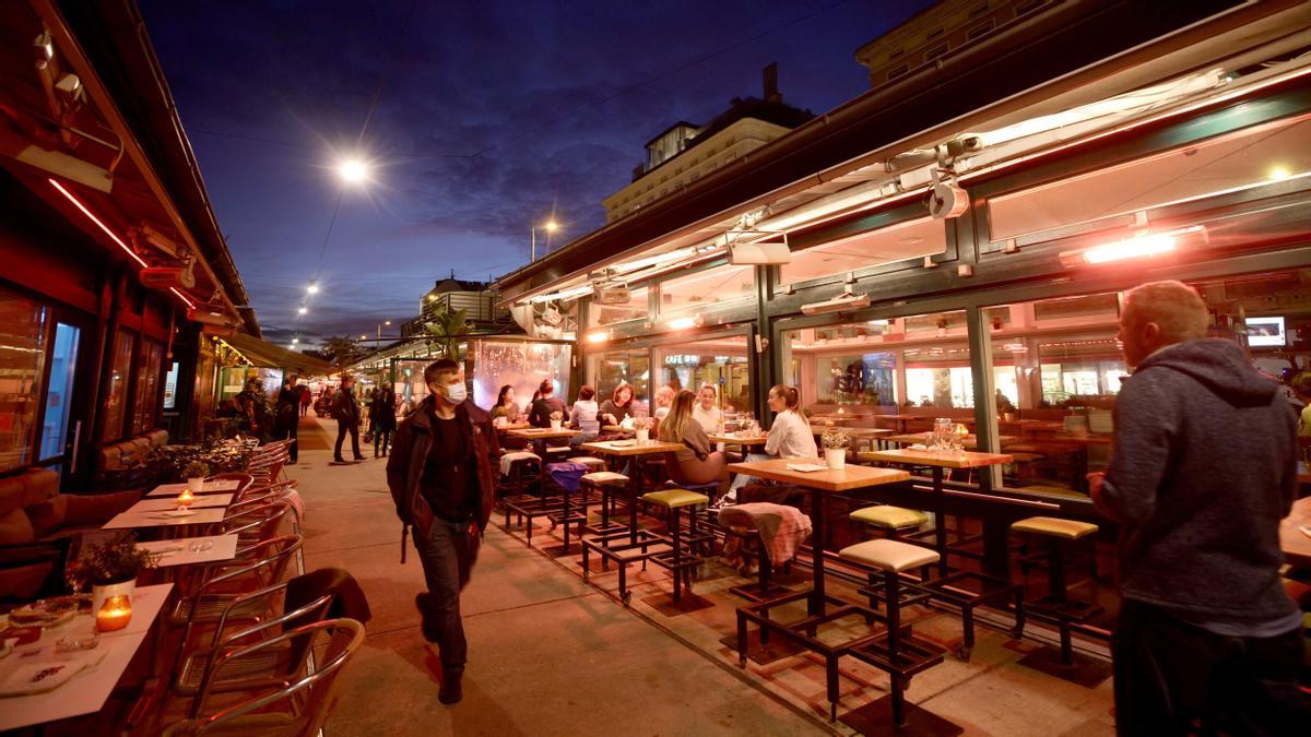 People share time at a cafe bar at Naschmarkt market the evening before the start of the second lockdown amid the coronavirus di