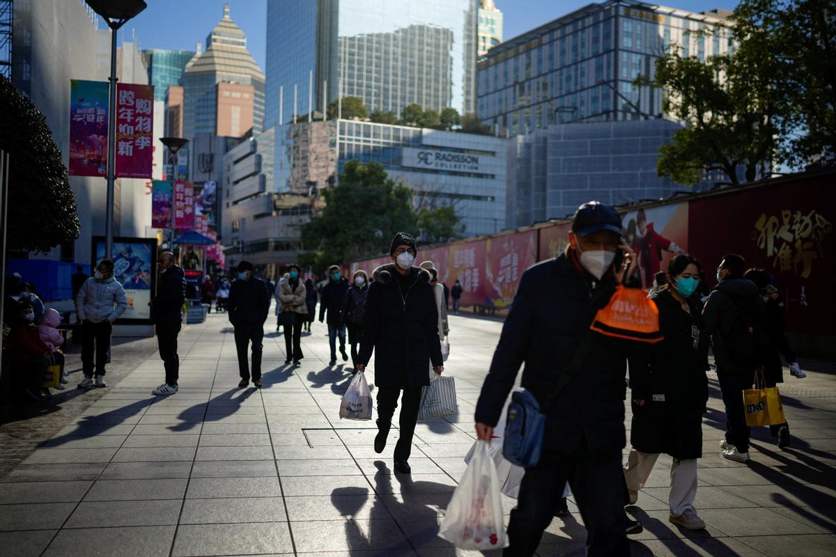 Las personas que usan máscaras protectoras caminan en un distrito comercial cuando China regresa al trabajo a pesar de los continuos brotes de la enfermedad por coronavirus.