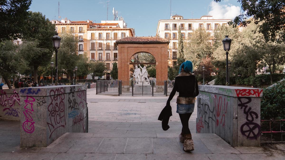 Una joven accede a la plaza llena de grafitis del Dos de Mayo, en Malasaña, Madrid.