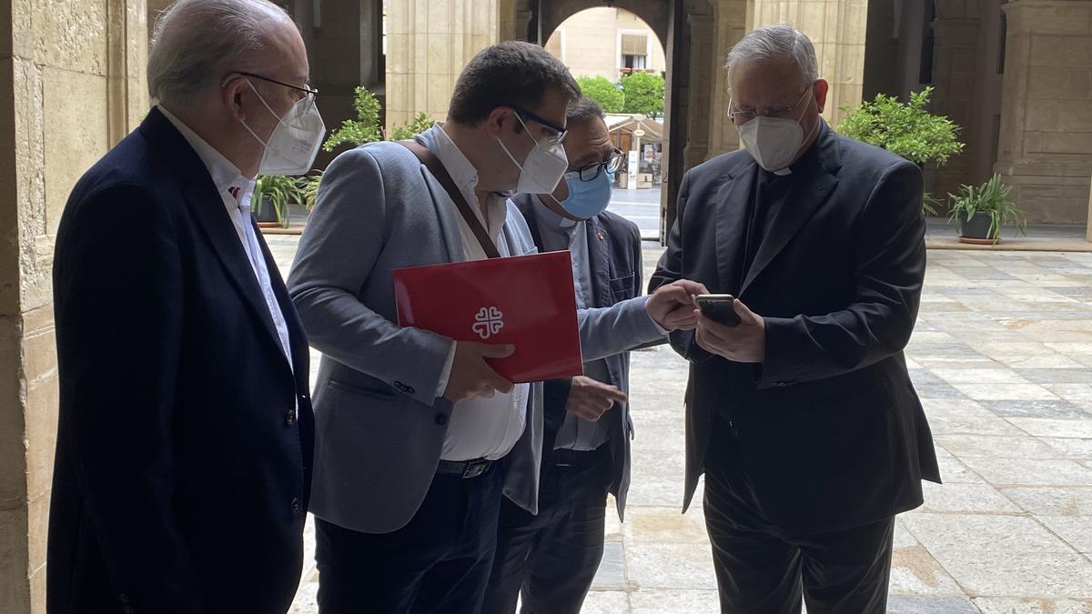 Lorca Planes (d) con gente de Cáritas antes de empezar la rueda de prensa.