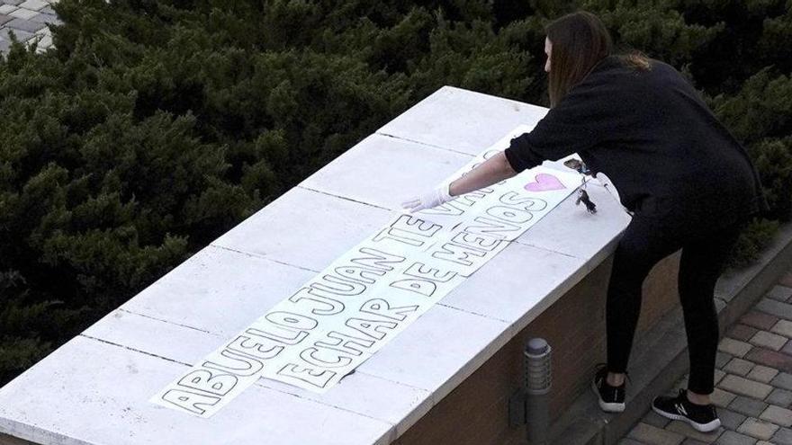 Una vecina de Boadilla del Monte (Madrid) pega una pancarta para honrar la muerte del abuelo paterno de su hijo.