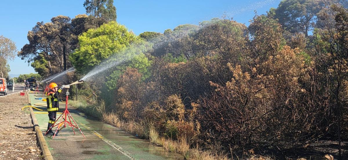 Un voluntario de Protección Civil lanza agua al perímetro