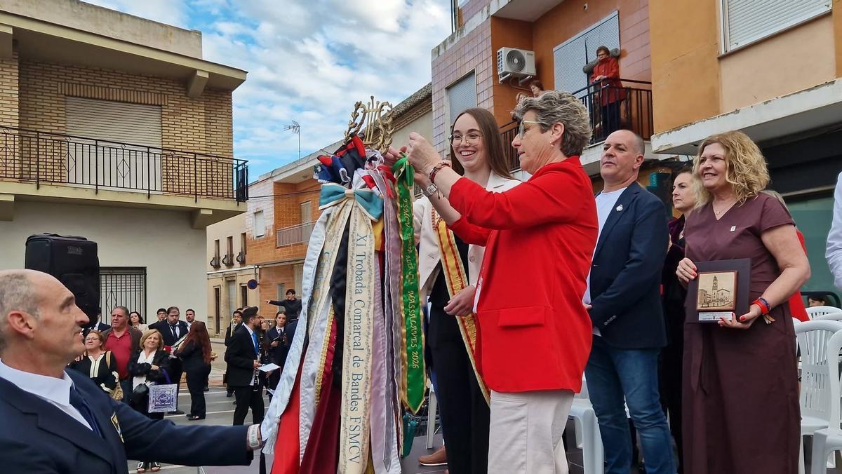 La alcaldesa de Massalavés coloca un cobartín de recuerdo a los estandartes de las sociedades participantes.