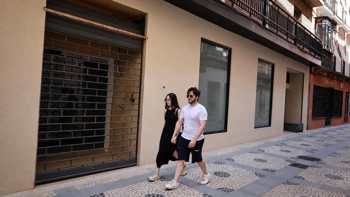 Dos jóvenes pasan junto al local de la calle San Juan que se convertirá en una galería de arte.