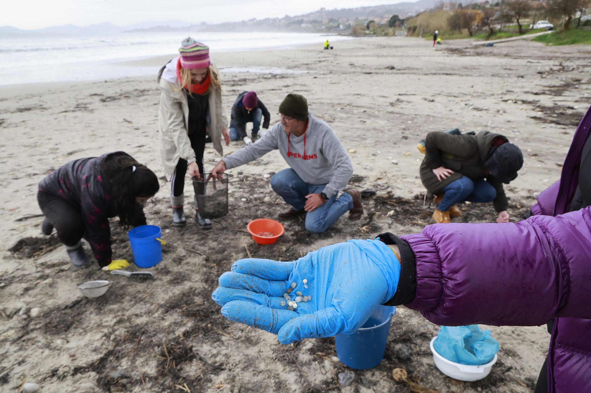 Voluntarios recogen pellets de plástico en la playa de Patros