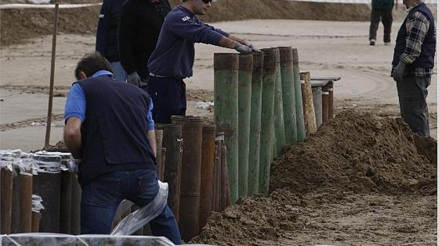 Los operarios montan los conjuntos de los cañones clavando los tubos en la arena.