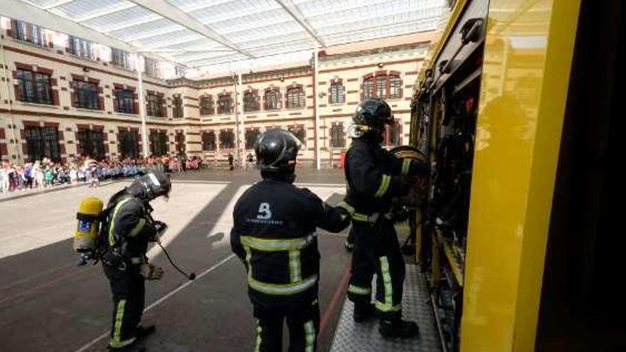 Los Bomberos, en el interior del colegio, con los niños al fondo.