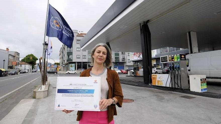Concha Vidal, ayer, con el certificado y la bandera azul en la gasolinera de A Corredoira. // Bernabé/J. Lalín