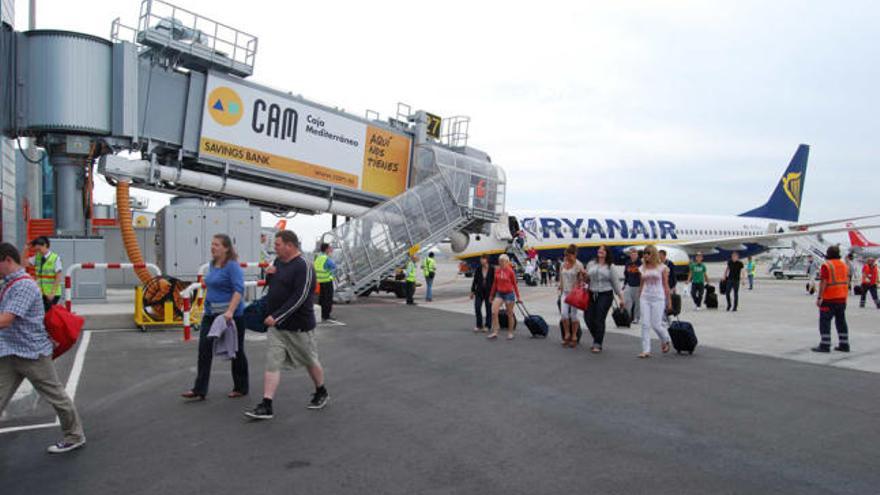 Los pasajeros del vuelo de Ryanair que unió el aeropuerto de Londres-Stanted con El Altet pasan junto a una pasarela telescópica tras descender del avión, ayer en el aeropuerto.