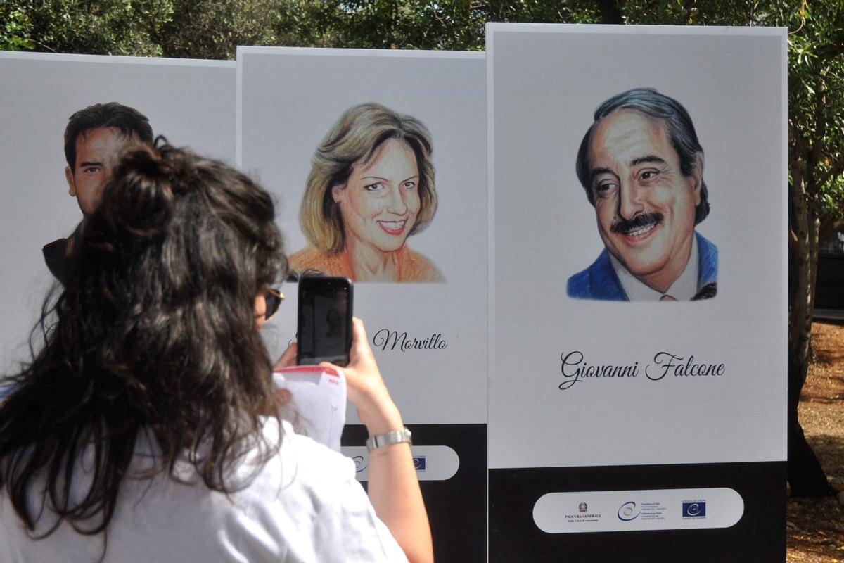Una mujer toma una foto de carteles con los retratos de Giovanni Falcone y su mujer, la también jueza Francesca Movillo, durante una ceremonia en recuerdo del 30 aniversario de su asesinato, en Palermo.