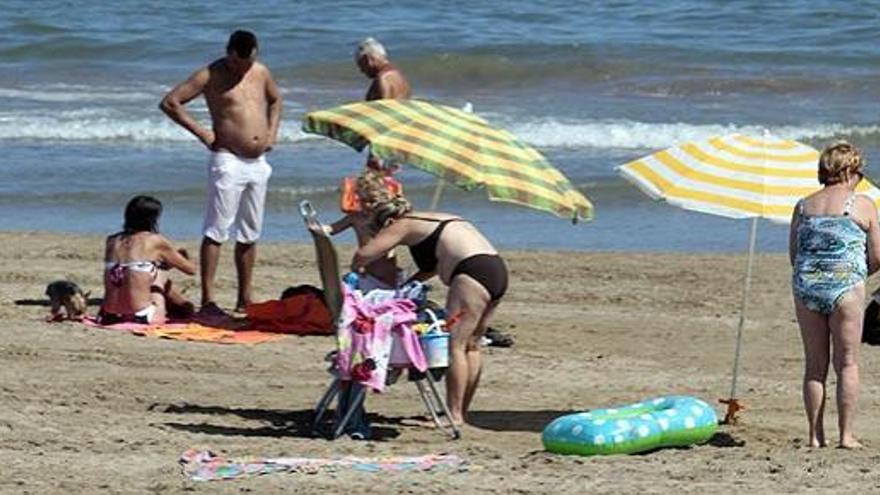 Varias personas toman el sol en la playa.