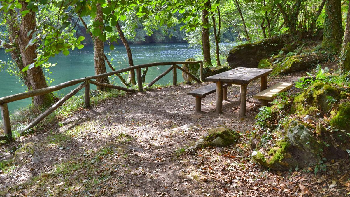 Mesas asomadas al río Navia en el área recreativa. 