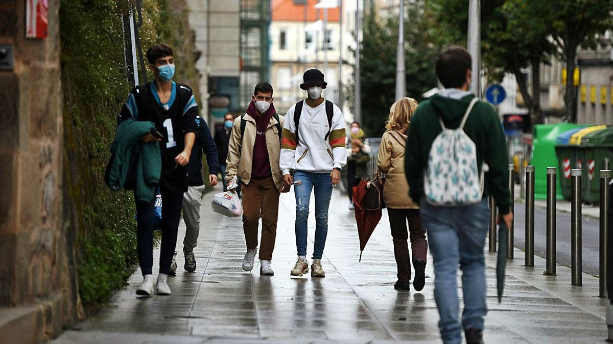 Unos jóvenes paseando por la calle con mascarilla. |   // GUSTAVO SANTOS’