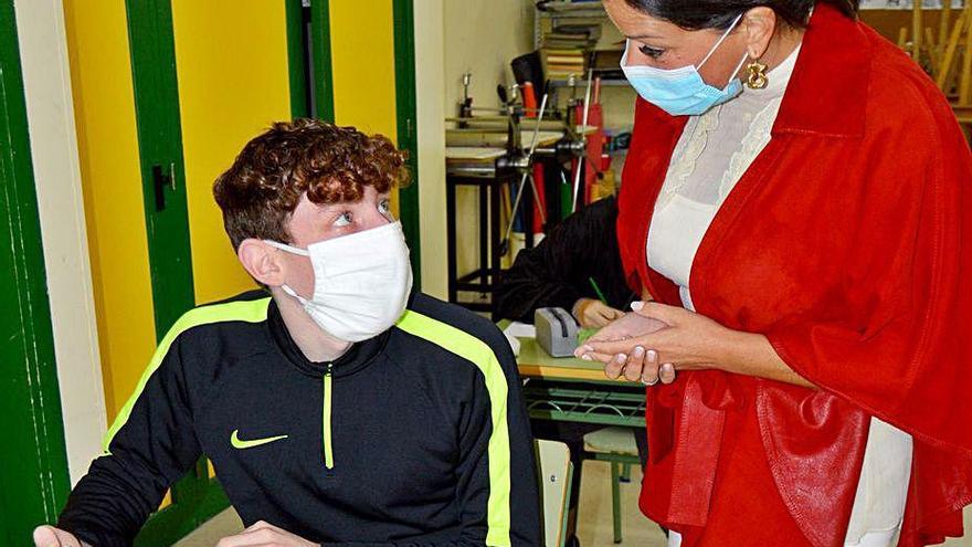 La alcaldesa, Nidia Arévalo, supervisa los diseños de las mascarillas para La Vuelta que le muestra un alumno.