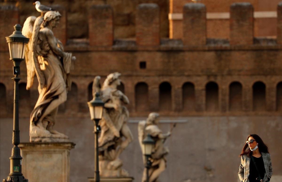 Una mujer camina sobre el Ponte Sant Angelo.