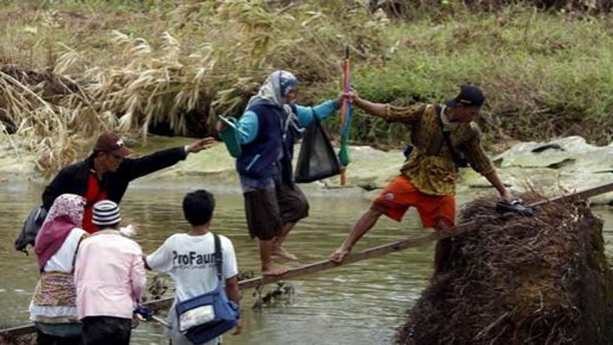 Supervivientes cruzan un río de camino a una localidad cercana de la devastada Sabeu Gunggung.