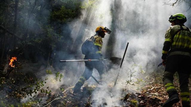 Bombers treballant en l’extinció del foc d’Osca, diumenge.  | ÓSCAR DEL POZO / AFP