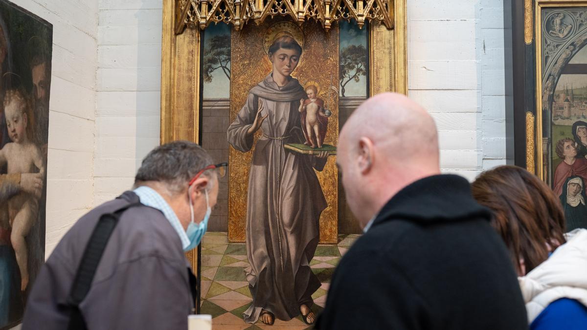 VARIAS PERSONAS CONTEMPLAN LA TABLA SAN ANTONIO DE PADUA