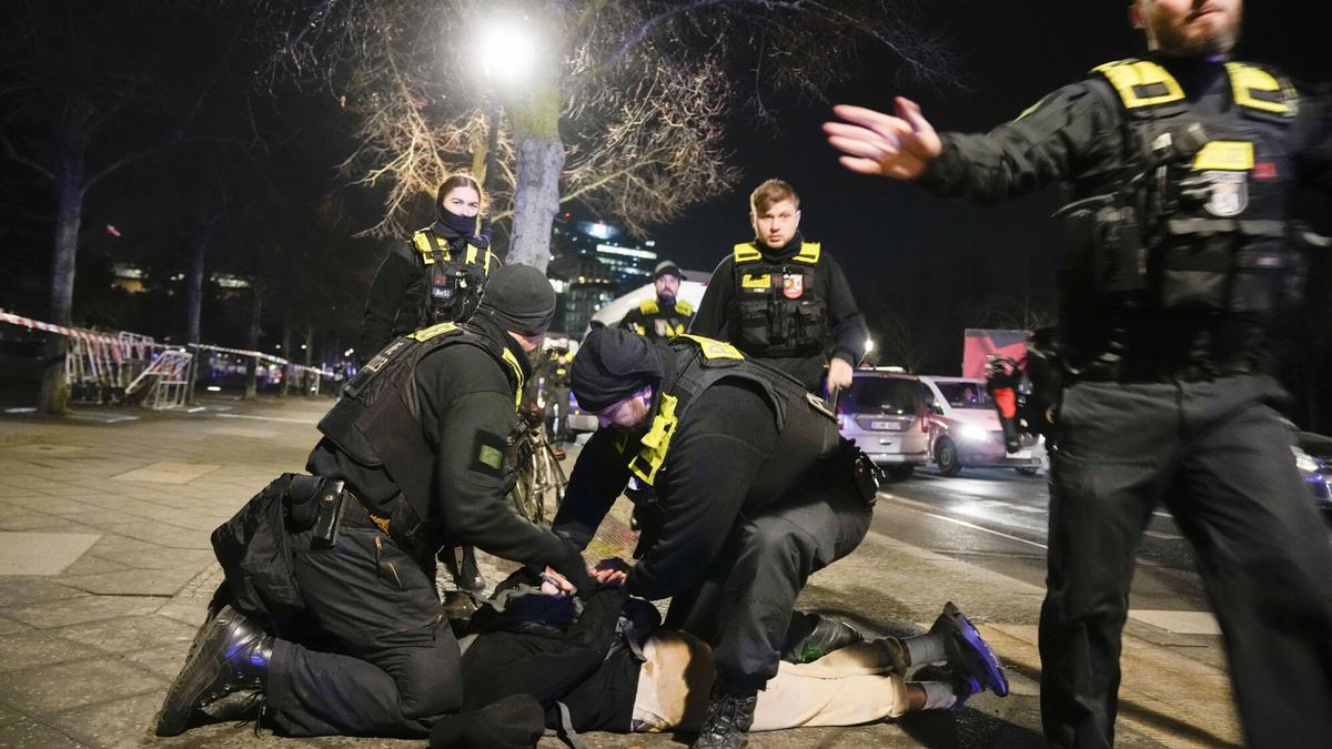 Police officers detain a man at the Holocaust memorial in Berlin, Germany, after another man was seriously injured, Friday, Feb. 21, 2025. (AP Photo/Ebrahim Noroozi)