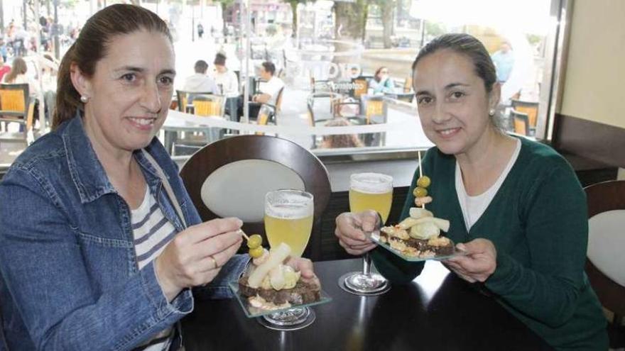 Dos mujeres toman una de las tapas servidas en la cafetería Aroma. // Santos Álvarez