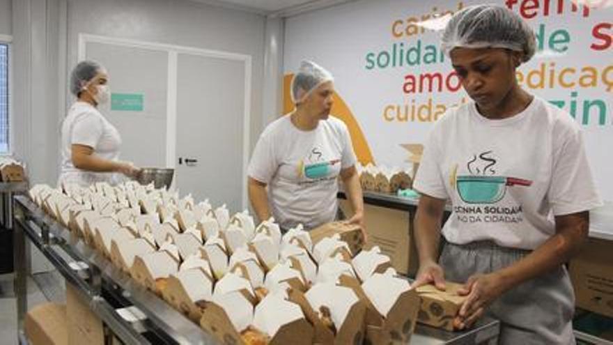 Trabajadoras de la organización Ação pela Cidadania preparan las raciones de comida que serán entregadas en la calle.