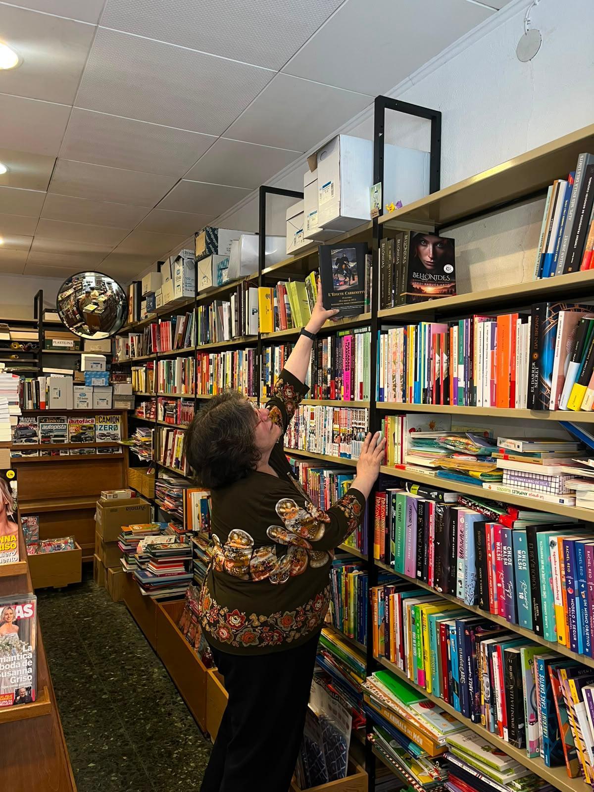 La Lourdes agafa del prestatge un llibre del seu pare