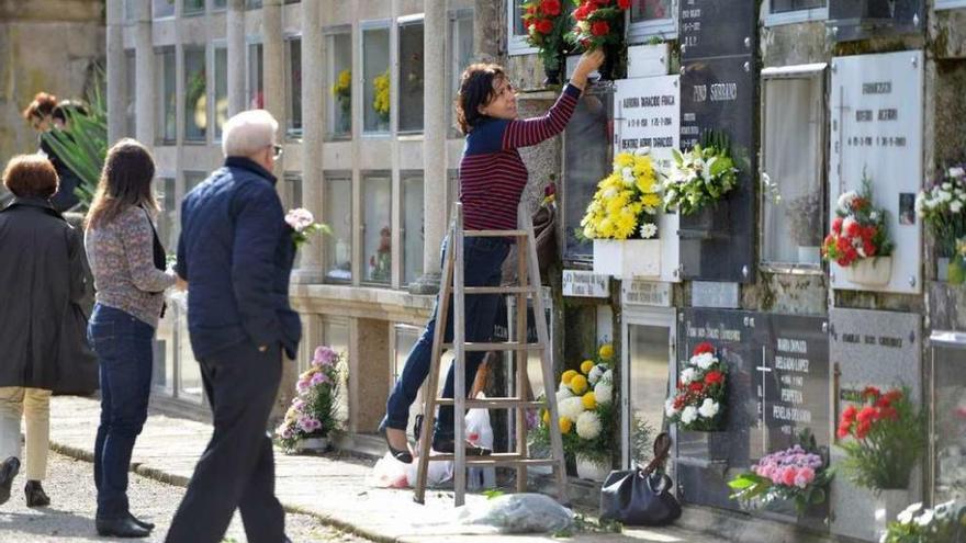 Una joven coloca flores en un nicho del cementerio de San Mauro. // Gustavo Santos