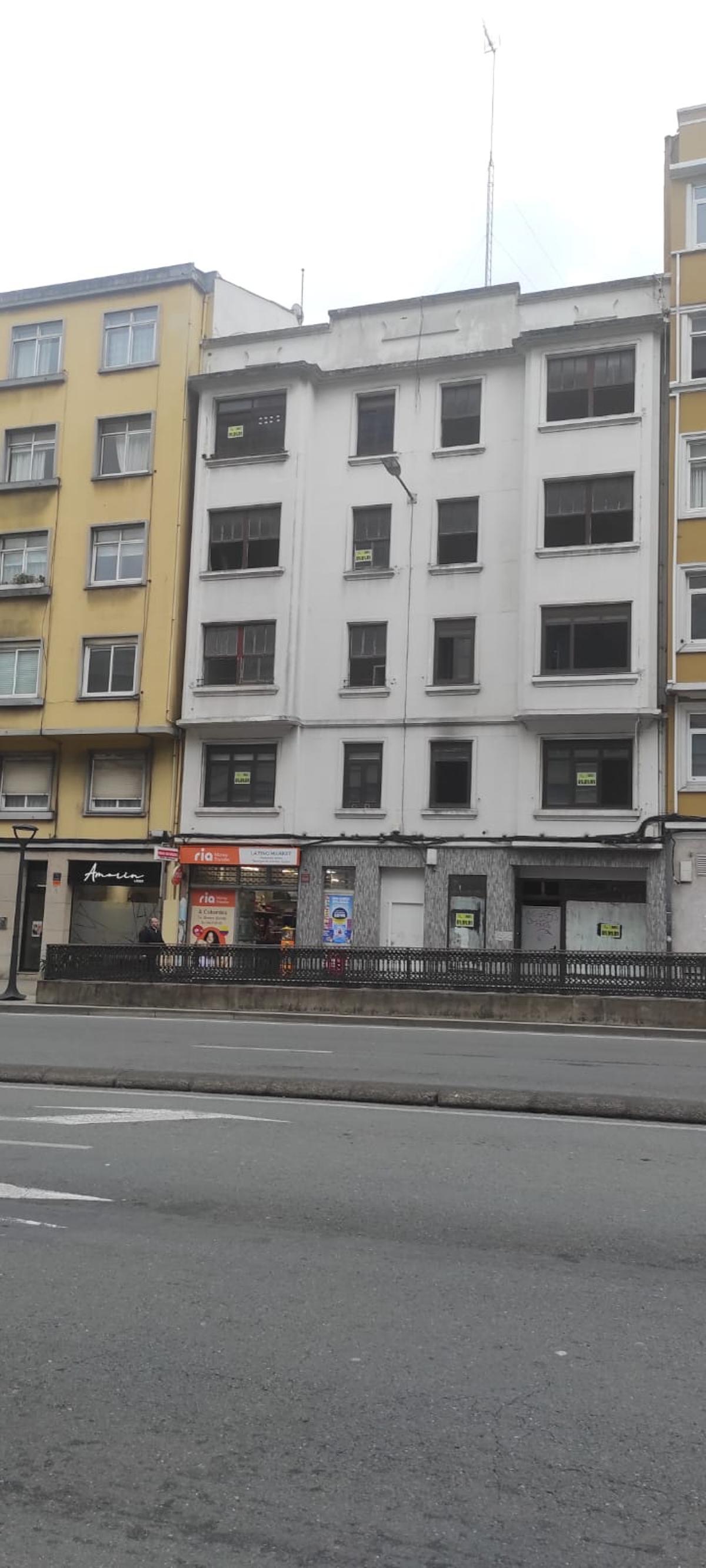 El edificio del número 137 de la ronda de Outeiro, con fachada blanca y carteles que anuncian la venta en las ventanas.