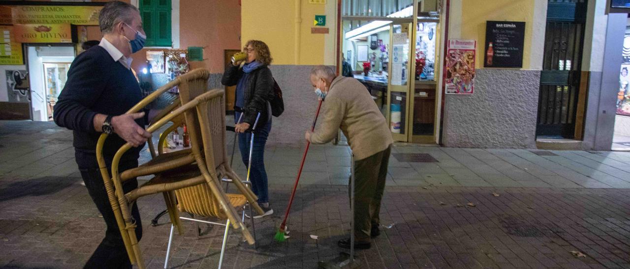 Los responsables del bar España de la calle Oms retiran el mobiliario de terraza el martes poco antes de las seis de la tarde, el día que entró en vigor el nuevo horario de cierre obligatorio