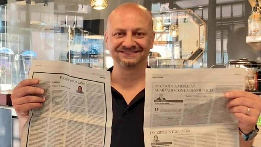 El autor y hostelero italiano, con el recorte del periódico con el artículo de Santos Guerra, en su café.