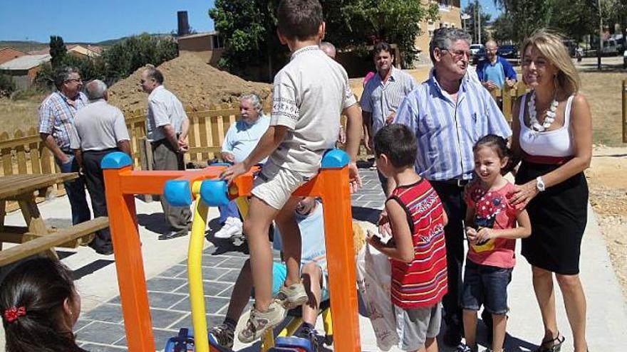 La subdelegada del Gobierno junto al alcalde de Riofrío conversa con algunos niños en el parque del pueblo.