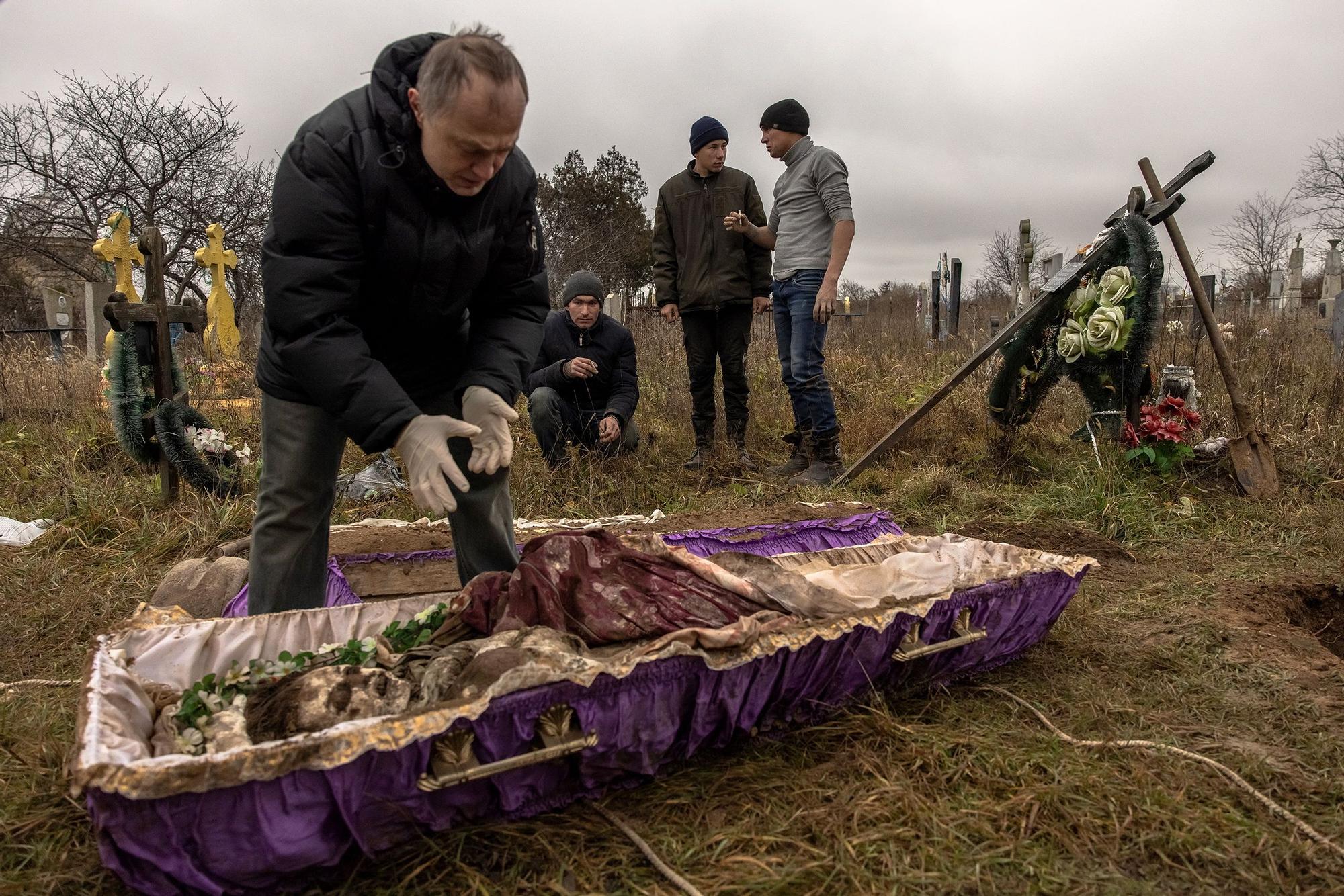 Residentes de un pueblo de Jersón aguardan la llegada de un forense que debe examinar los restos de una adolescente presuntamente asesinada durante la ocupación rusa, el pasado 29 de noviembre en el cementerio de Pravdyne.