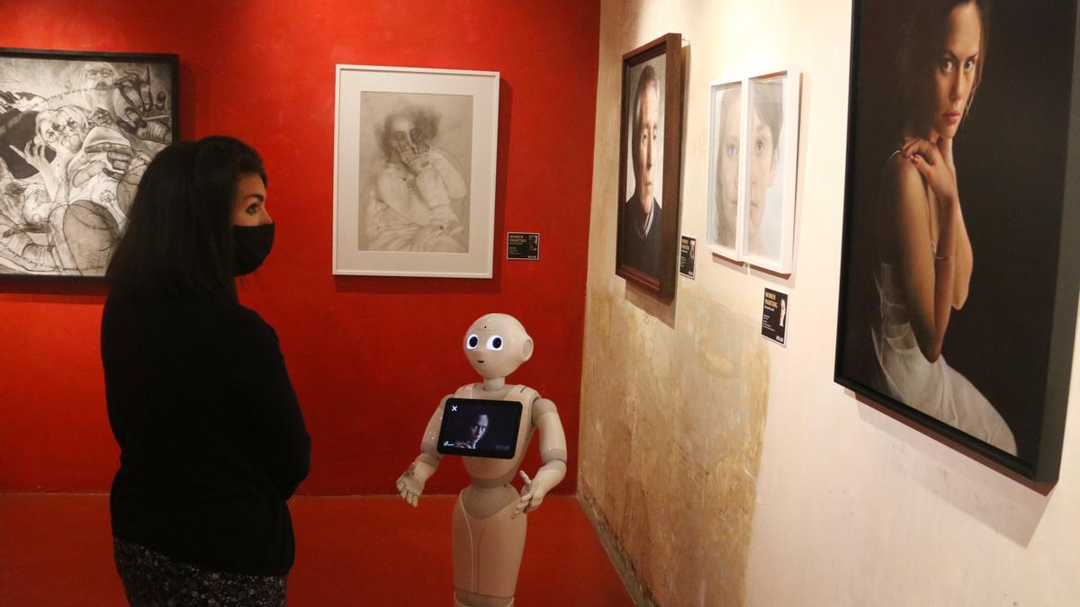 Una noia observa un quadre escoltant les explicacions del robot Pepper al MEAM