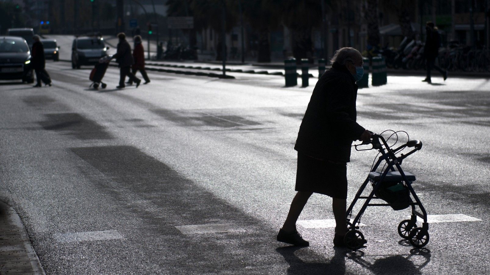 Una señora mayor cruza apoyada en su caminador la calle Marina de Barcelona