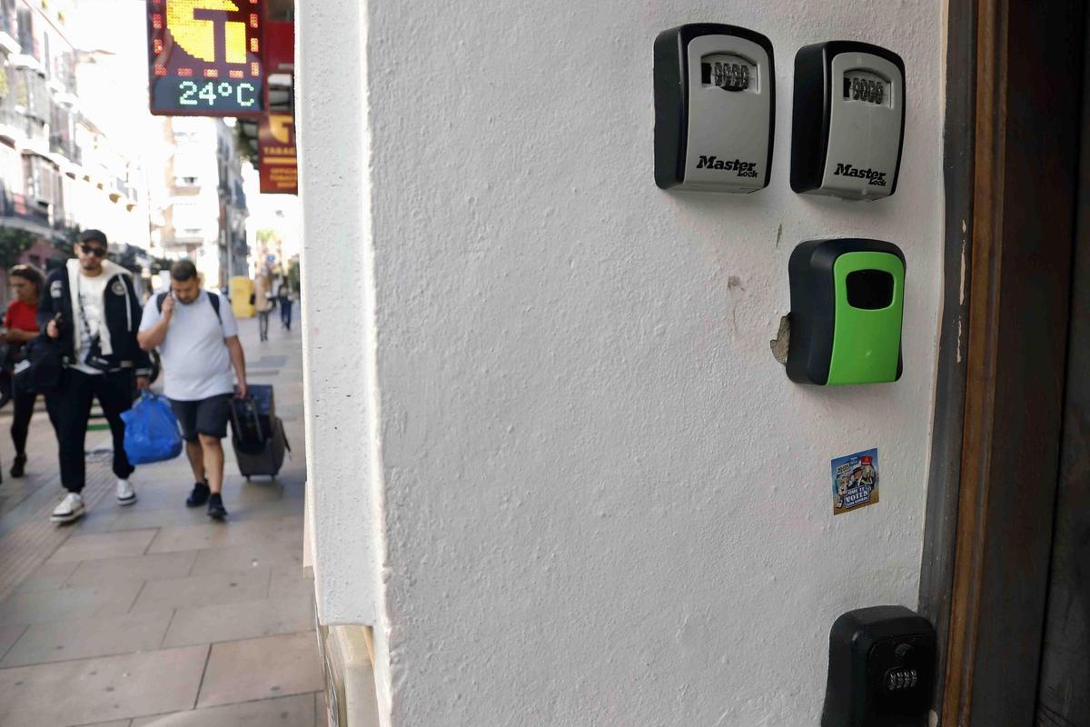 Varios turistas pasan cerca de cajas o cajetillas de llaves de los pisos turísticos que hay en el casco histórico de Málaga