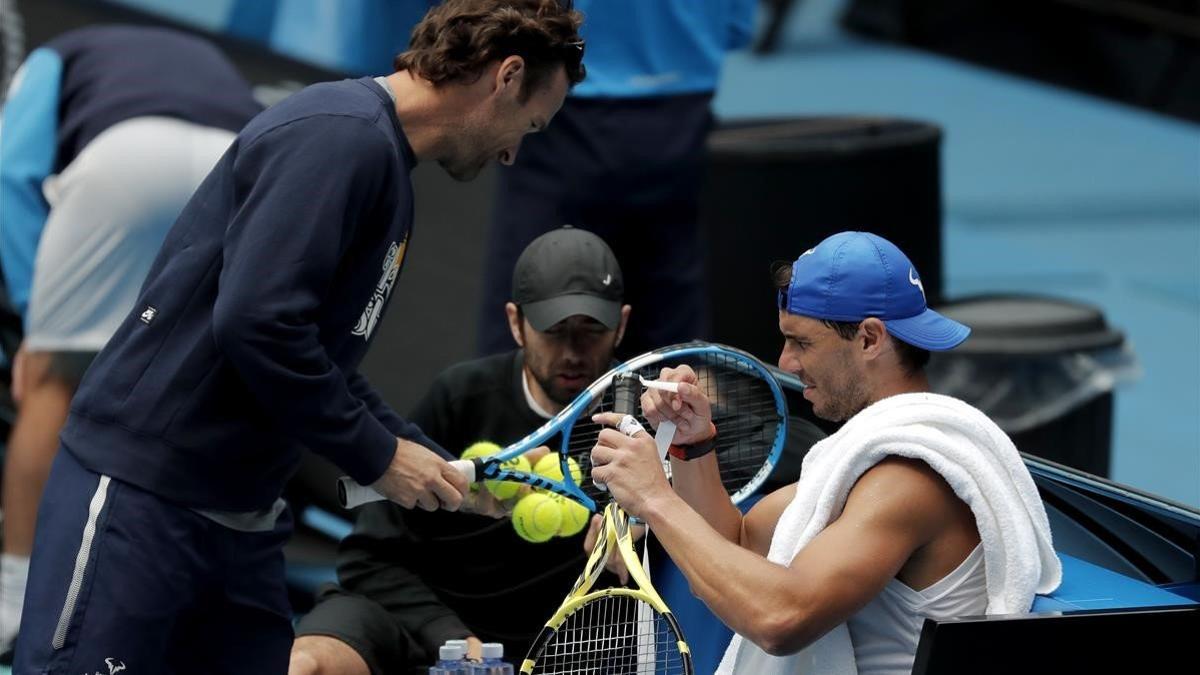 Nadal pone cinta en su raqueta ante la presencia de su entrenador, Carlos Moya.