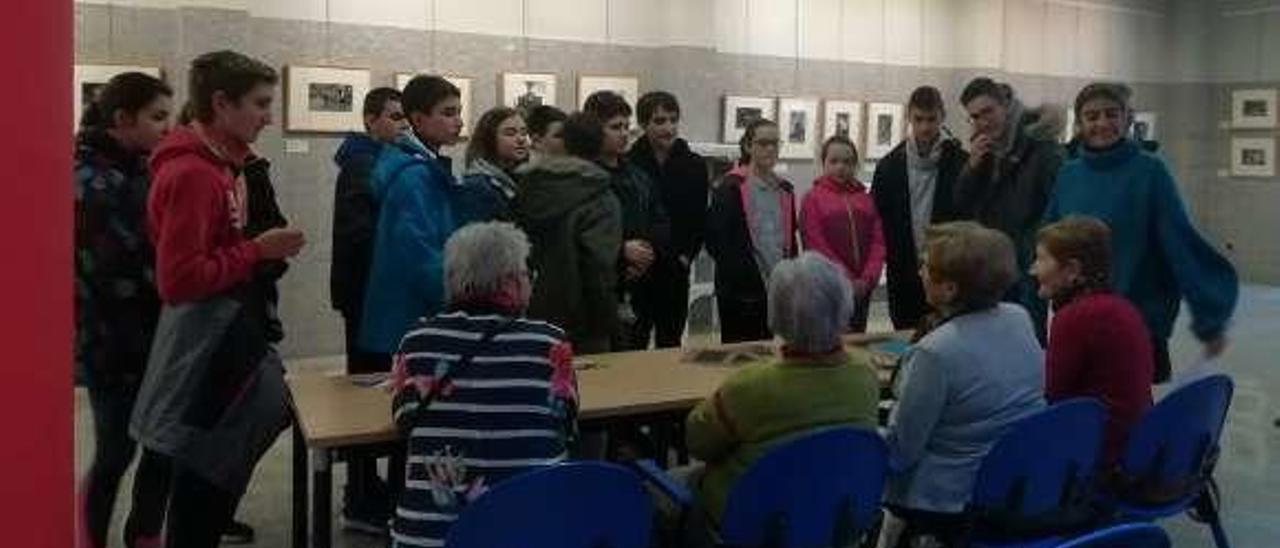 Alumnos del IES de Infiesto visitan la exposición de Valentín Vega en la Casa de Cultura en compañía de las usuarias del taller de memoria.