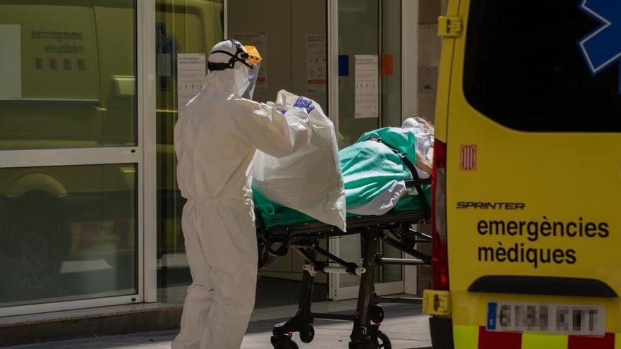 Un sanitari transporta una persona contagiada amb coronavirus a una ambulància