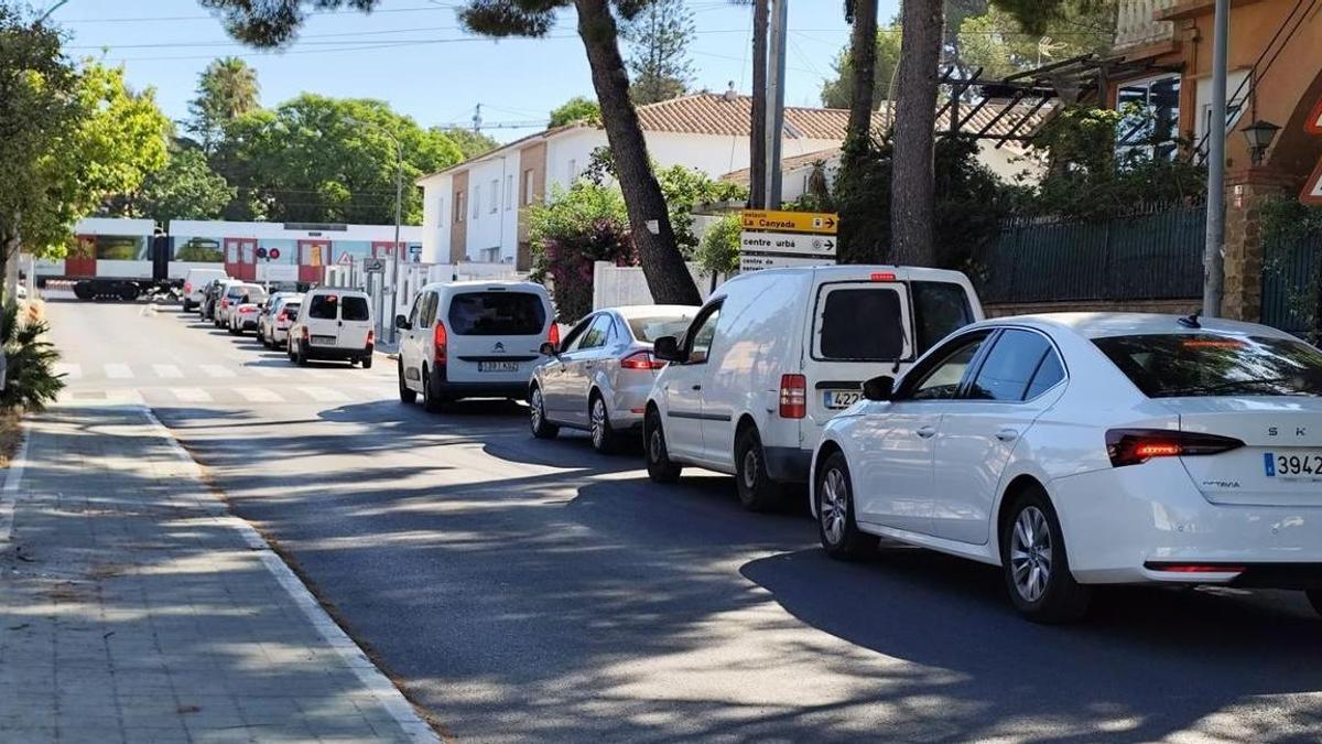 Cola de vehículos ante la barrera bajada por el paso del convoy de FGV.